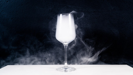 wine glas filled with smoke on a white table with a black background, smoke in glas, 