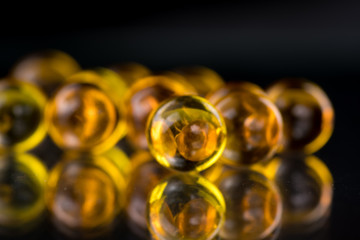 Yellow and orange medicine capsules containing fish oil, omega 3