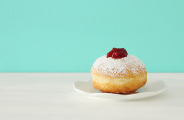 Image of jewish holiday Hanukkah with traditional doughnut on the table.