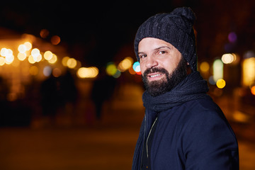 Hombre joven con barba y elegante en la calle, en una noche de invierno