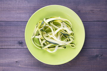 Plate with heap zucchini spaghetti on a wooden table