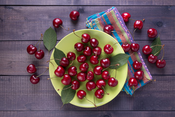 Heap of red cherries on plate on wooden background. Fresh delicious berries on boards.