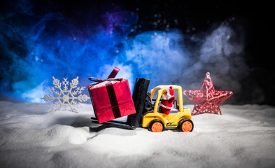 Miniature Gift Box by Forklift Machine on snow ,Determined Image for Christmas Holiday and Happy New Year Gift Celebration concept.