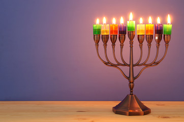 image of jewish holiday Hanukkah background with menorah (traditional candelabra) and colorful oil candles.