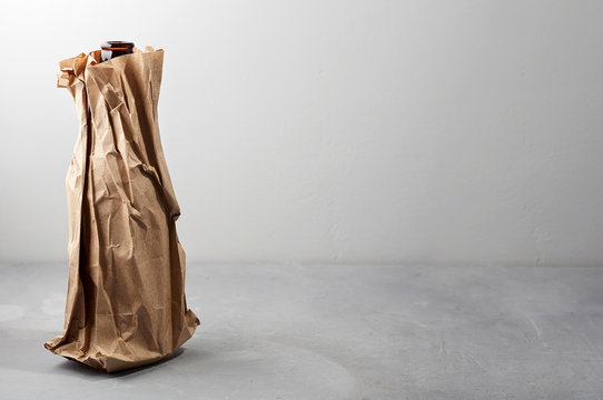 Beer Bottle In The Paper Bag On Gray Concrete Background