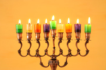 Fototapeta premium image of jewish holiday Hanukkah background with menorah (traditional candelabra) and colorful oil candles.