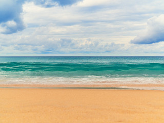 View of the paradise beach with golden sand, waves on the sea and the sky with clouds