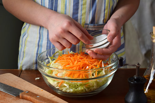 Woman cook sauerkraut or salad on wooden background. Step 3 - Salt the cabbage. Fermented preserved vegetables food concept.