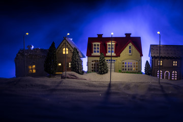 Little decorative houses, beautiful festive still life, cute small houses at night, Night city real bokeh background, happy winter holidays. Selective focus