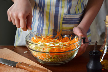 Woman cook sauerkraut or salad on wooden background. Step 4 - Stir the cabbage. Fermented preserved vegetables food concept.