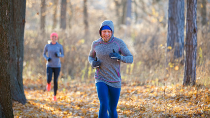 Fototapeta premium Young sporty man and woman jogging in park