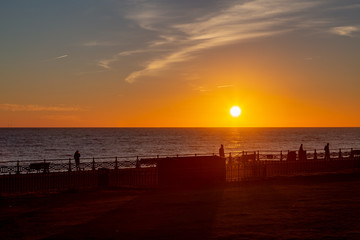 Fototapeta na wymiar Silhouettes on Brighton Promenade at Sunset