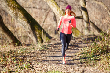 Young woman jogging on trail in autumn park