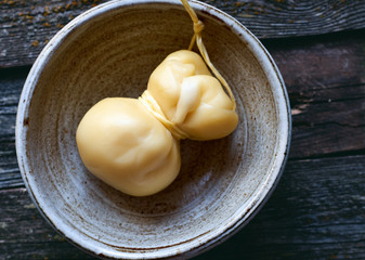 Healthy homemade old Italian provolone cheese in bowl on wooden table top view