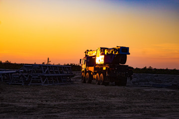 all-terrain truck-mounted crane at a construction site in the background of the sunset