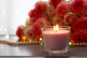 Obraz na płótnie Canvas Burning candles with rose fresh flowers bouquet on gray table, close up home interior details