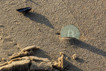 Bitcoin Münze im Sand am Strand mit Muschel