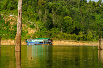 Naklejka premium Houseboat moored near the lakeshore under bright sunny day over beautiful nature background