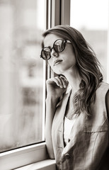 Grunge girl in sunglasses near window . Image in black and white color style