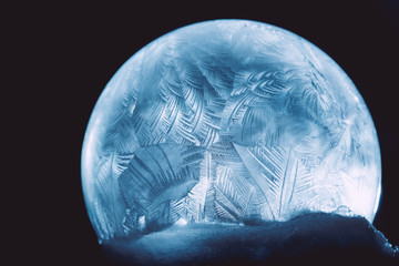 Naklejka na ściany i meble Frosty christmas winter pattern. Ice patterns frosted on ball of a soap against black copy space abstract background. Natural Christmas magic ball.