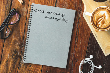 Hot coffee and notebook with greeting message.