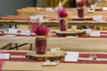 wedding table settings with wooden platter, mason jars and burgundy and brown colouring.