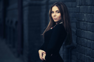 Happy young fashion woman in black dress walking in city street