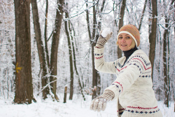 Girl throwing a snowball. Games in the winter forest. Fun in the open air. Happy woman. Christmas mood. Winter vacation in the ski resort. Sculpt lumps of snow. Man in the winter forest. Women's smile