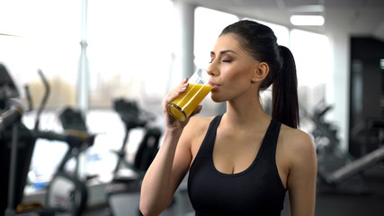 Fit woman drinking refreshing juice from glass after gym workout, health care