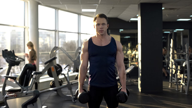 Male Bodybuilder Lifting Weight, Doing Dumbbell Curls, Morning Workout In Gym