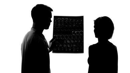 Silhouettes of young doctor showing bad mri results to female patient, treatment