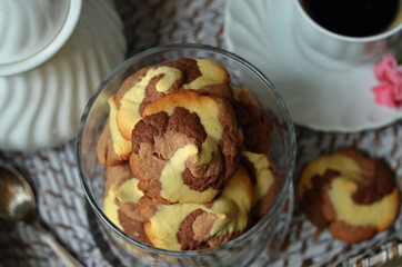 Three-colored cookies in glass. A cup of coffee on a white saucer