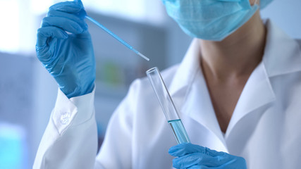 Chemistry scientist pouring blue liquid in lab tube, new detergents development