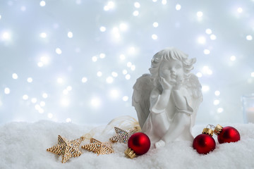 Fototapeta na wymiar White christmas - cute angel in snow, bokeh lights in background