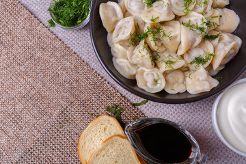 boiled dumplings national dish of many nations with sour cream, soy sauce and greens on the table