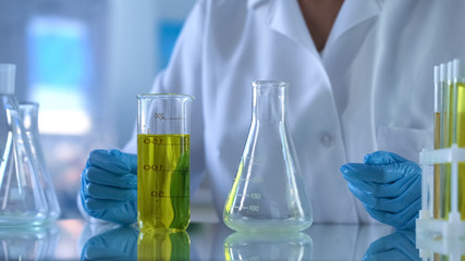 Scientist looking at test tube with yellow substance, petrol quality analysis