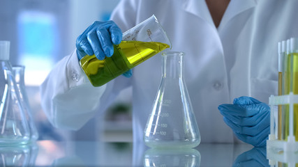 Researcher pouring yellow substance in test tube, oil quality, new petrol