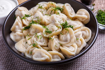 boiled dumplings national dish of many nations with sour cream, soy sauce and greens on the table