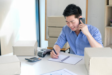 Young male business owner working at home, taking customer orders by phone.