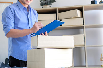 Young male business owner working at home checking box delivery to the customer.