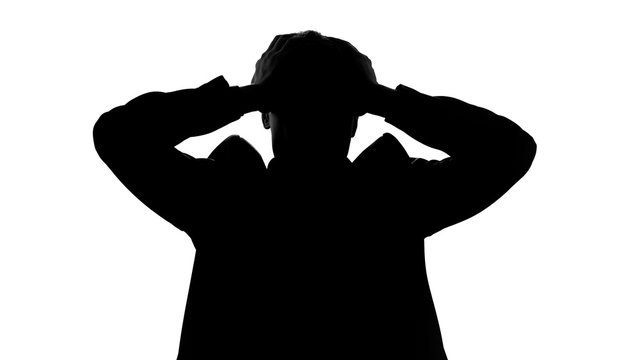 Man suffers from headache, silhouette grasps head, voices in mind, schizophrenia