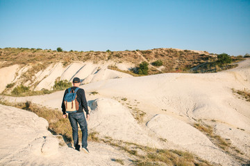 Fototapeta premium A tourist with a backpack travels in the mountains of Cappadocia in Turkey. A solitary walking tour in the mountains.