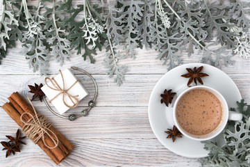 A gift for your beloved for any holiday - a fashionable jewellery bracelet with charms in a beautiful white box. Cineraria leaves, vanilla and cinnamon, a cup of coffee. Hygge Danish happiness. Autumn