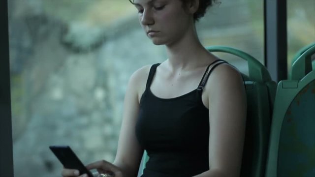 Girl alone riding on city bus using Smartphone.