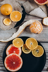 Delicious various types of citrus fruit in plates on wooden background