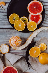 Delicious various types of citrus fruit in plates on wooden background