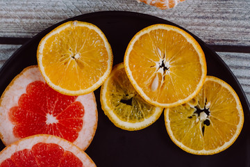 Delicious various types of citrus fruit in plates on wooden background