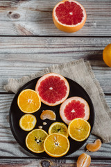 Delicious various types of citrus fruit in plates on wooden background