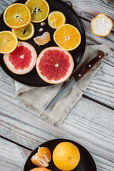 Delicious various types of citrus fruit in plates on wooden background
