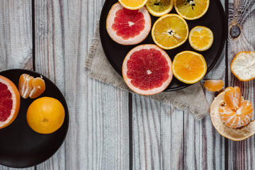 Delicious various types of citrus fruit in plates on wooden background